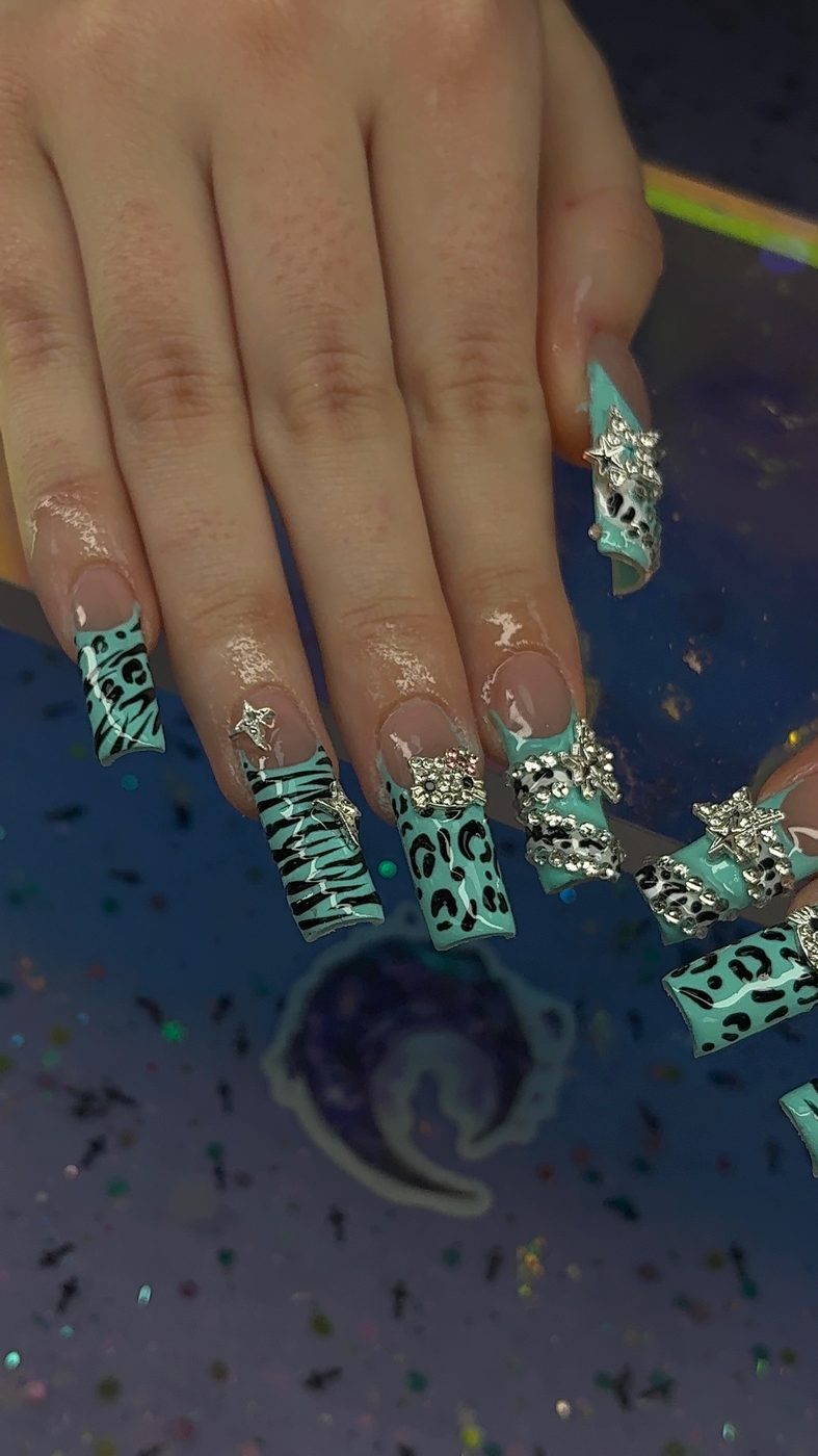 Lia nail art with teal animal print tips, black striping, and rhinestone accents.
