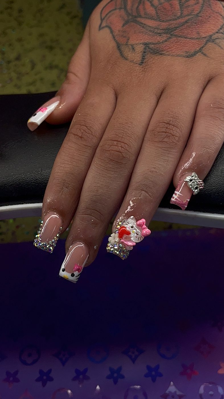 Lia nail art with pink, white, and black mixed designs, rhinestones, and 3D floral accents.